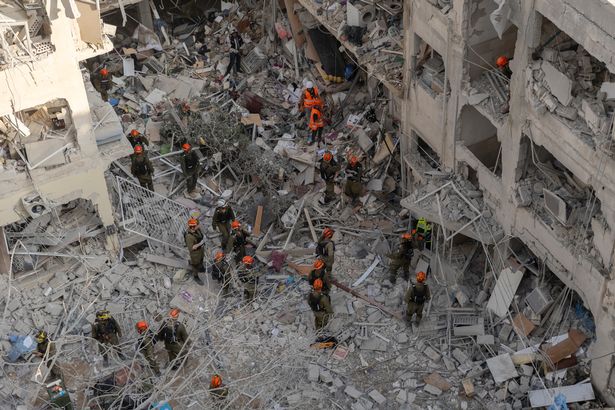 جنود الطوارئ والإنقاذ يبحثون عن أشخاص محاصرين حول المباني التي تضررت بشدة بعد إضراب صاروخ خلال الليل