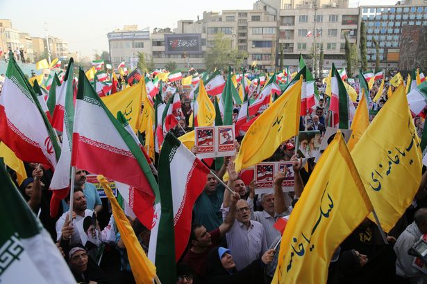 الناس ، الذين يحملون لافتات وأعلام ، يجتمعون للاحتفال بوقف إطلاق النار بين إيران وإسرائيل في طهران