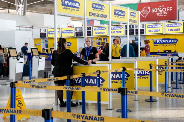 يقف موظفو Ryanair بجوار تسجيل الوصول للذات ومواقع إسقاط الأكياس الذاتية في مكتب تسجيل الوصول في Ryanair في London Stansted