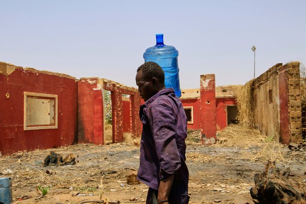 رجل يحمل حاوية مياه عبر مبنى تضرر خلال الحرب الأهلية في الخرطوم ، السودان ، 25 مايو 2025.
