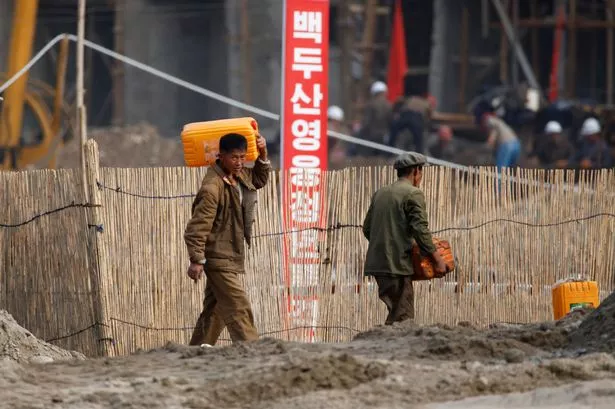 يعيد العمال بناء المنازل في سينويجو ، كوريا الشمالية
