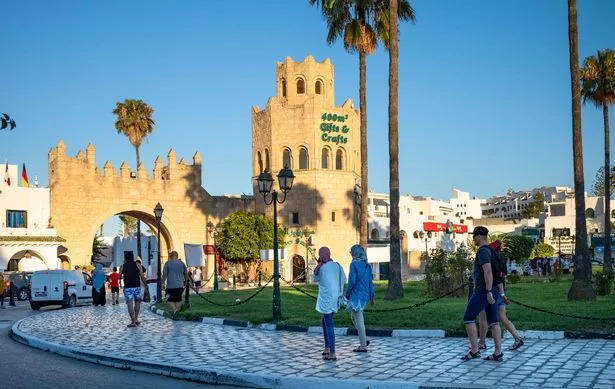 السياح والزوار يسيرون نحو بوابة مدخل إلى المرسى في بورت إل كانتوي في تونس