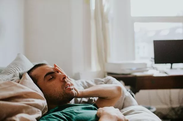 استيقظ رجل للتو في بيئة محلية ، إما غرفة معيشة أو غرفة نوم. 