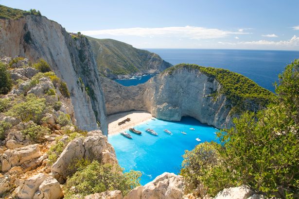 منظر من Clifftop فوق المياه الفيروزية لخليج Navagio (AKA Shipwreck Bay ، Smugglers Cove) ، قوارب متعة ترتكز على الشاطئ ، بالقرب من Anafonitria ، Zakynthos (المعروف أيضًا باسم زانتي ، زاكينثوس) ، الجزر الأيونية ، اليونان ، أوروبا.