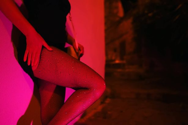 امرأة في جوارب شبكة السمك تنتظر في شارع الليل