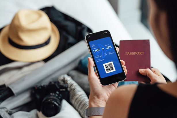 على ما يجب عرض امرأة شابة تحمل هاتفًا ذكيًا بتذاكر طيران رقمية أثناء تعبئة حقيبة. السفر bleisure. السفر العطلات.