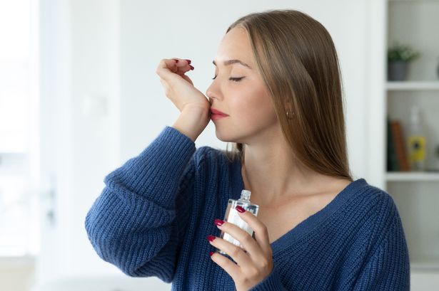 امرأة شابة تشم رائحة العطر على معصمها 