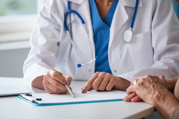 القسم المتوسط ​​للطبيب الإناث جالسة على المكتب في مكتب ومناقشة نتائج الاختبار مع امرأة كبرى