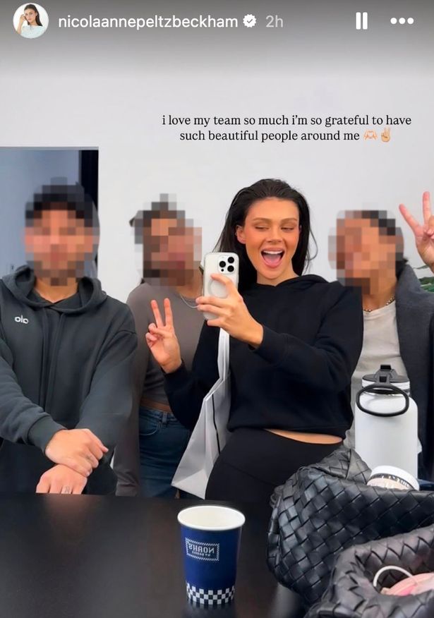 نيكولا بيلتز ، في قمة أسود ولباس طماق ، تتظاهر بتقليل صورة شخصية في مرآة بجانب ثلاثة من 