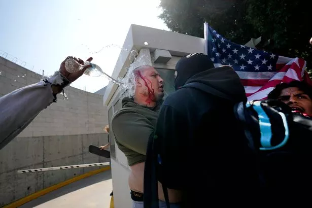 الشخص الذي كان يرتدي قبعة ماغا ، وفقًا للشهود ، يواجهه مجموعة من المتظاهرين بعد أن طاردته في وسط مدينة لوس أنجلوس ، الاثنين ، 9 يونيو 2025 (AP Photo/Jae C. Hong)