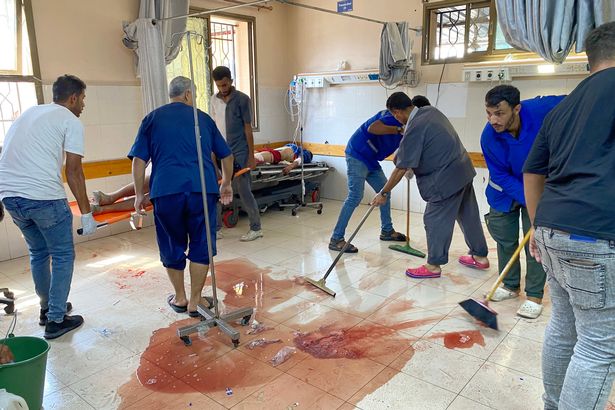 يقوم المسعفون بتنظيف أرضية الدم حيث يهتم الآخرون بالفلسطينيين الذين أصيبوا