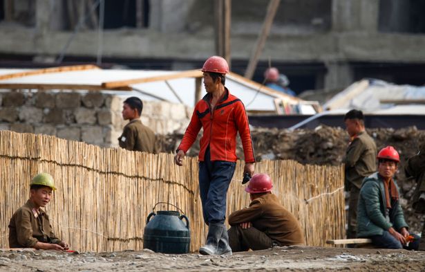 يعيد العمال بناء المنازل في سينويجو ، كوريا الشمالية