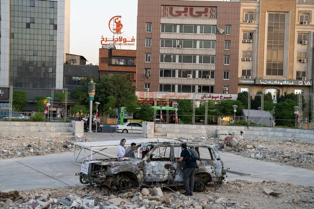 يسير الشعب الإيراني عبر حطام المباني المدمرة ، وهو تركيب مضاد للحرب في مربع في وسط مدينة طهران