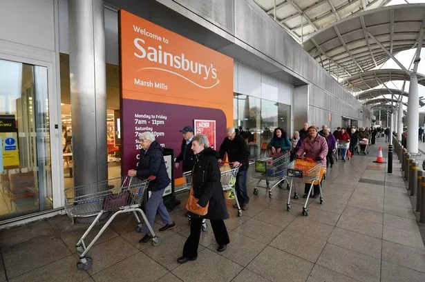 صورة لخط من الأشخاص ، مع عربات التسوق ، تصطف في الانتظار لدخول فرع من السوبر ماركت Sainsbury's