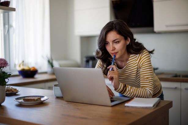 امرأة شابة تستخدم كمبيوتر محمول أثناء العمل من المنزل