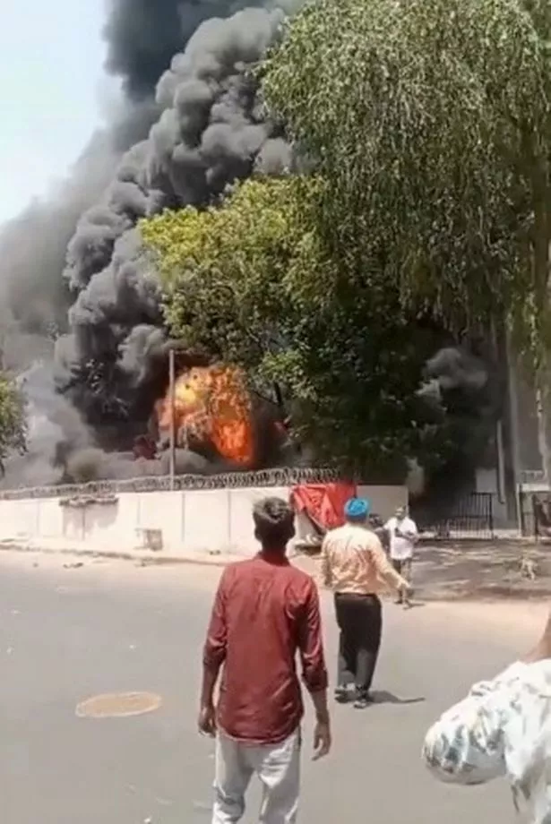 الناجي فيشواشكومار راميش (أعلى أبيض في الخلف)) مسافة مع الطائرة على بعد النار في المسافة 