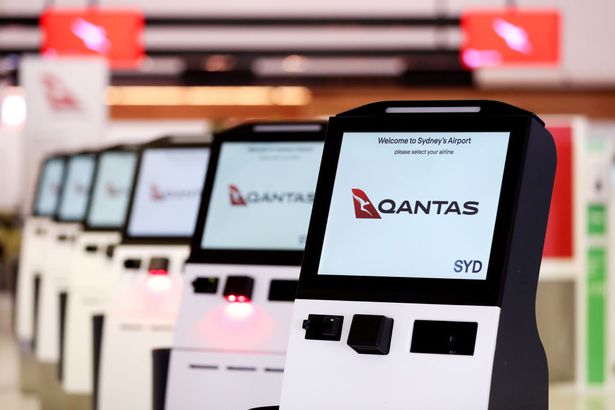 صورة العلامة التجارية لـ Qantas على أكشاك تسجيل الوصول الآلية داخل محطة المغادرة الدولية