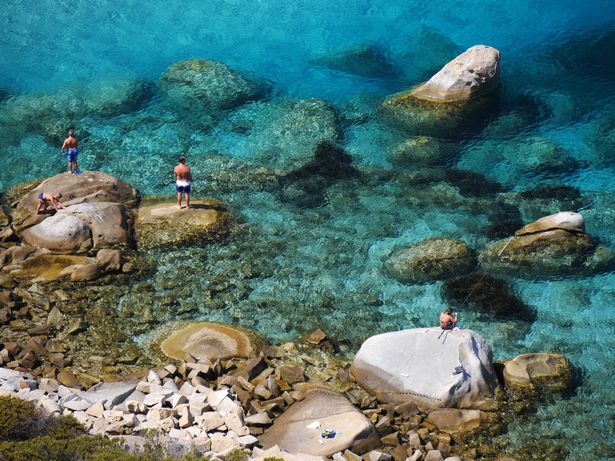 الناس يصطادون في البحر الأبيض المتوسط في Spiaggia di Porto Giunco. موقع بالقرب من قرية Villasimius في شبه جزيرة كابو كربونارا في جنوب جزيرة سردينيا / إيطاليا.