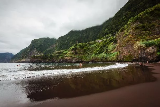 الصورة التي التقطها في وضح النهار من قبل غائم في منتصف الشاطئ الرملي الأسود يسمى "Praia do Porto" في Seixal ، ماديرا.