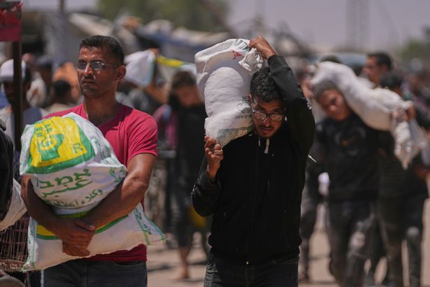يحمل الفلسطينيون أكياسًا تحتوي على حزم الطعام والإنسانية 
