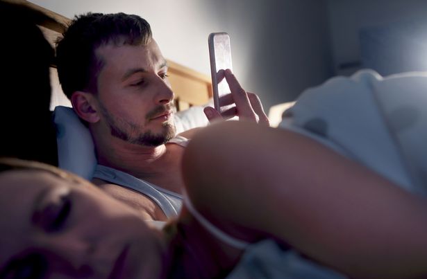 رجل يمرح على الهاتف بينما ينام الشريك