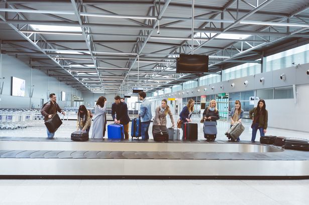 الركاب الذين يجمعون الأمتعة من حزام ناقل الأمتعة في محطة المطار
