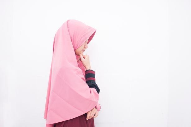 لقطة لامرأة شابة مدروسة جذابة تقف على جدار أبيض