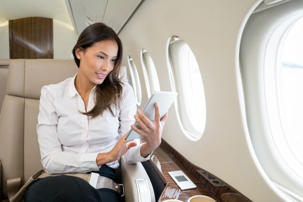 صورة المرأة التي تستخدم جهاز iPad الخاص بها على متن طائرة