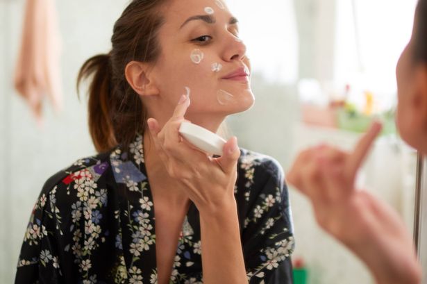 أنثى شابة في الحمام تبحث في المرآة وتهتم بجلد وجهها.