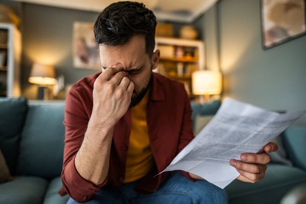 رجل أعمال شاب مكتئب يمر بأعمال ورقية في المنزل ولديه مشاكل مع ديون غير مدفوعة الأجر.