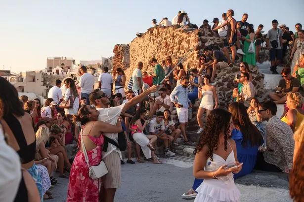 يجتمع السياح في قرية OIA في جزيرة Santorini اليونانية لمشاهدة غروب الشمس في 20 يوليو 2024. مثل الوجهات السياحية الشهيرة الأخرى ، فإن جزيرة Cycladic التي تطفو على بركان تقترب من التشبع المفرط ، وتريد الآن تقييد عدد سفن الرحلات البحرية. (تصوير Aris Oikonomou / AFP) (تصوير Aris Oikonomou / AFP عبر Getty Images)