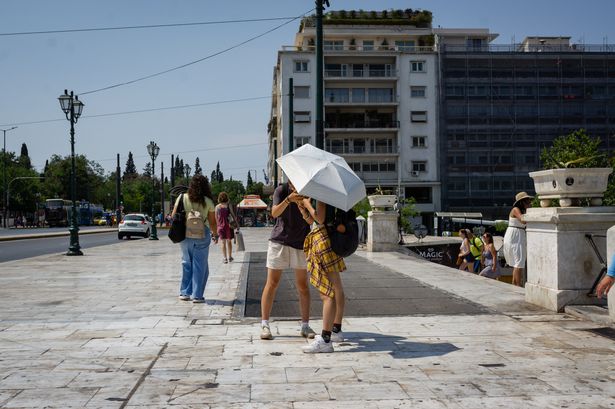 سائحون يملأون من الشمس في ساحة Syntagma في أثينا ، اليونان. المخاوف ترتفع بشأن 