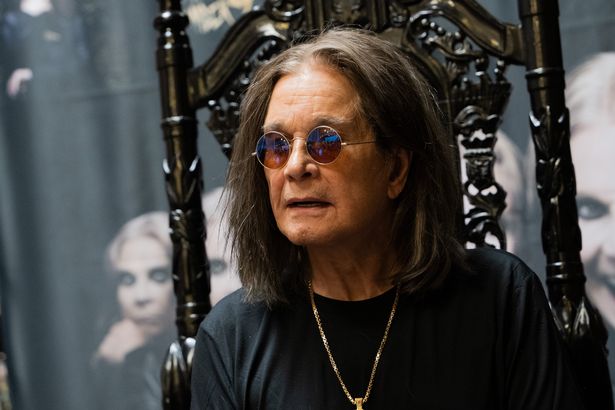 جلس Ozzy Osbourne في قمة أسود ونظارات شمسية.
