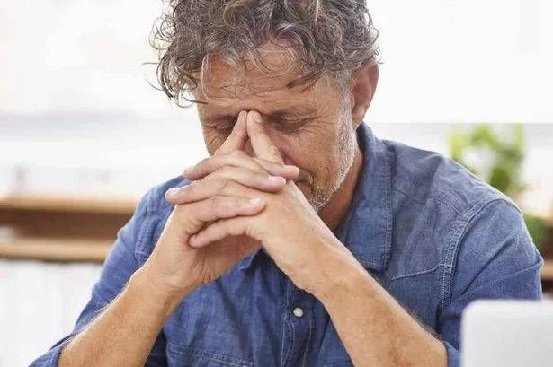 رجل أكبر سنا يمسك وجهه في يديه.