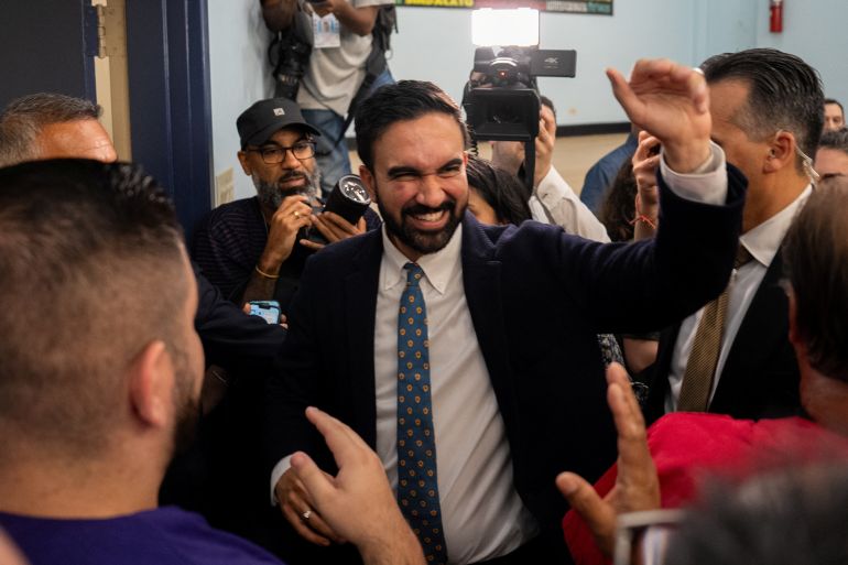 موجات زوران مامداني بينما يغادر حدثًا ، محاطًا بكاميرات الإعلام.
