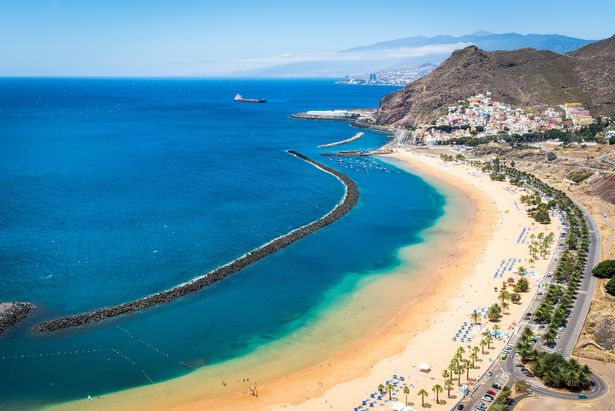 في المقدمة - Playa de Las Teresitas Beach و Small Village of San Andreas ، في الجزء الخلفي - جزء من Tenerife's Capital - Santa Cruz de Tenerife و Auditorio de Tenerife. جبل تييد مرئي في الظهر البعيدة.