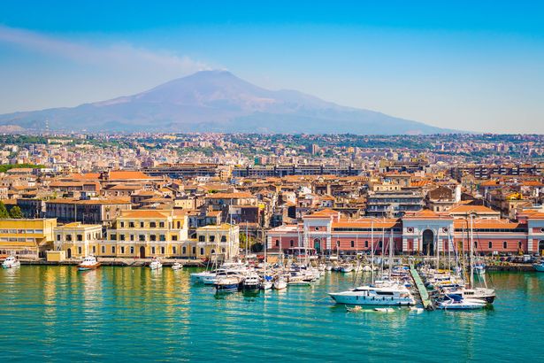 عرض ميناء Catania Cruise مع تدخين بركان etna في الخلفية.