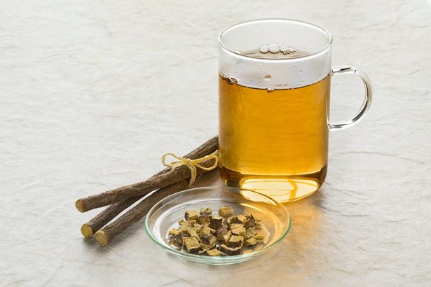 كوب من شاي عرق السوس وقطع الجذور أمام الكأس