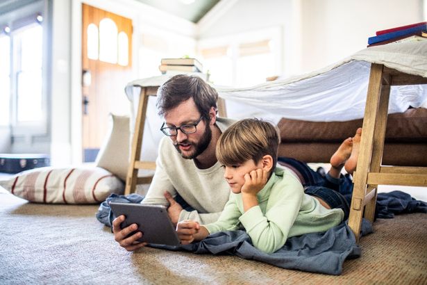 الأب والابن يشاهدون الكمبيوتر اللوحي الرقمي في الحصن محلي الصنع