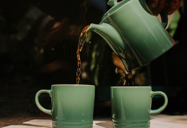 كؤوس خضراء يجلس في الخارج. يتم سكب الشاي في أكواب من وعاء الشاي المطابق.