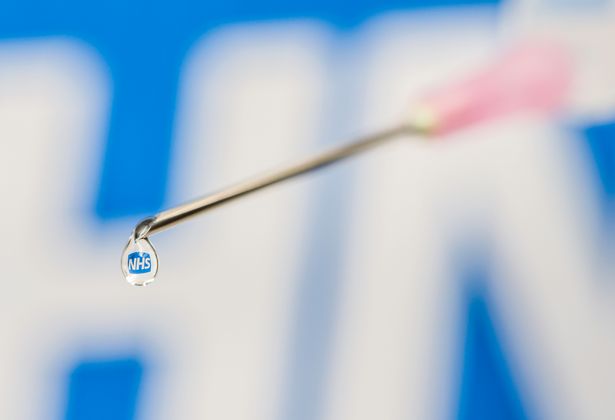 الملخص - الإبرة المقطوعة والمحاقن ، مع شعار NHS ينعكس في التنقيط.