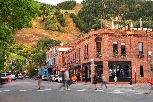 يمشي الناس جنبًا إلى جنب مع متاجر البيع بالتجزئة الفاخرة والمطاعم الفاخرة في مدينة Aspen Colorado التاريخي للتزلج