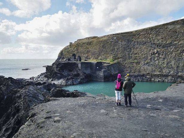 اثنان من المتنزهين ينظران إلى Blue Lagoon بالقرب من Abereiddi - ويلز