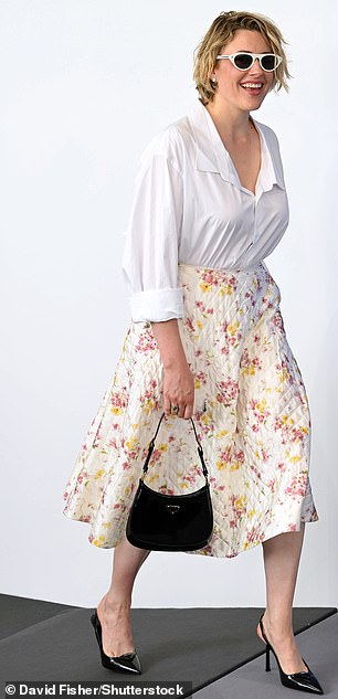 قطعت Greta شخصية جلامية في تنورة Midi الأزهار وبلوزة بيضاء منخفضة القطع أثناء حضورها Photocall