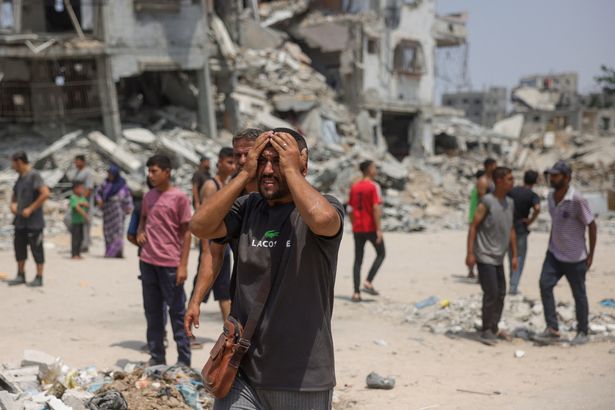 يتفاعل رجل مع قيام المسعفون بتخليص الضربات الإسرائيلية