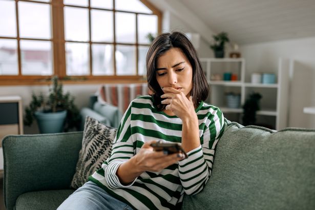 ألبوم صورة لسيدة شابة معنية تبحث على شاشة الهاتف الذكي ، وتقلق على الشؤون المالية