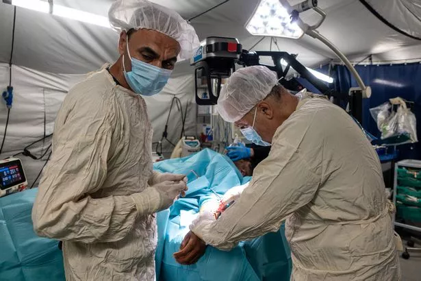 يقوم الطبيب وفريقه الجراحي بإزالة الشظايا من ذراع رجل في أحد المستشفيات الميدانية في المملكة المتحدة.