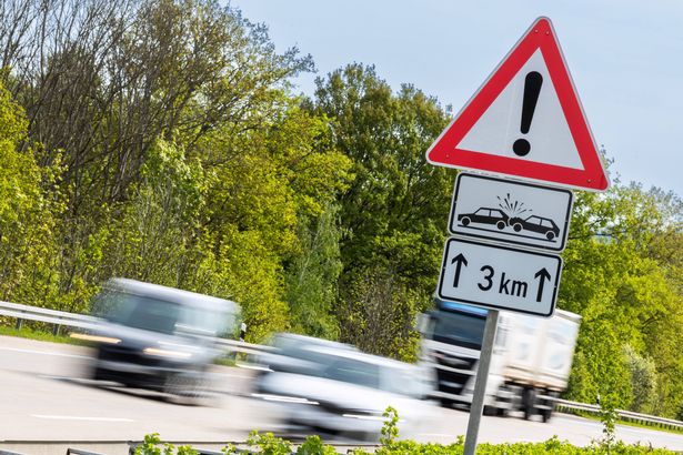 الشاحنات والسيارات على Autobahn الألمانية مع علامة تحذير الحوادث. علامة الطريق تعني "الاهتمام ، خطر خاص من الحادث على بعد كيلومترات ثلاثة كيلومترات القادمة"