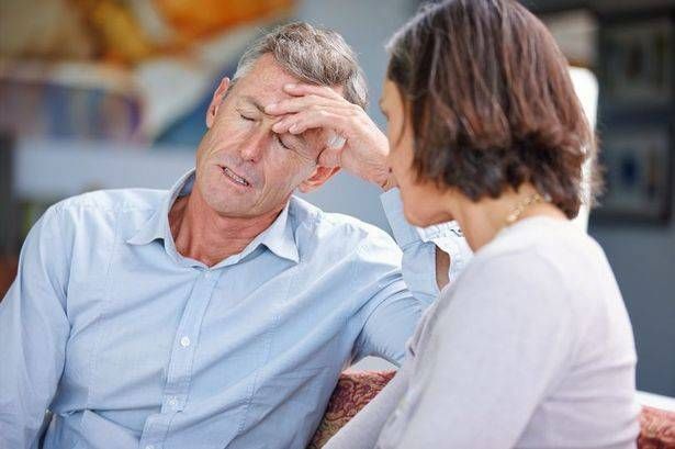 رجل وامرأة يجلسون على أريكة ، الرجل أغلقت عينيه ويمسك يده على رأسه