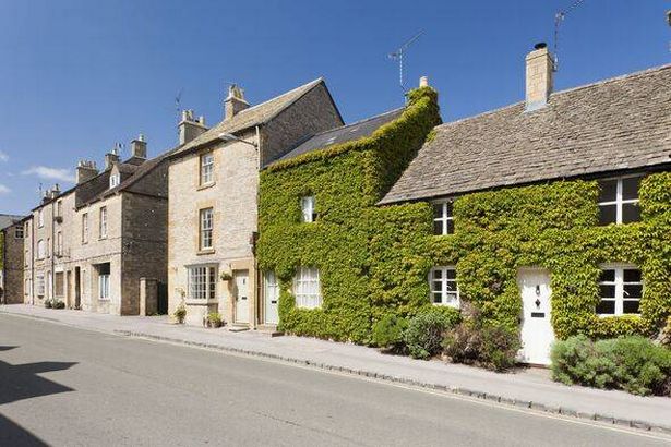 شارع من المنازل الريفية التي تم بناؤها من Cotswold Stone في Stow على Wold ، واحدة مغطاة في اللبلاب